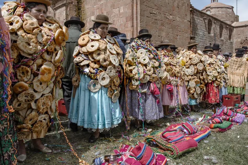 Mujeres aymaras cargando los panes ornamentados de la Rosqueada de Pomata