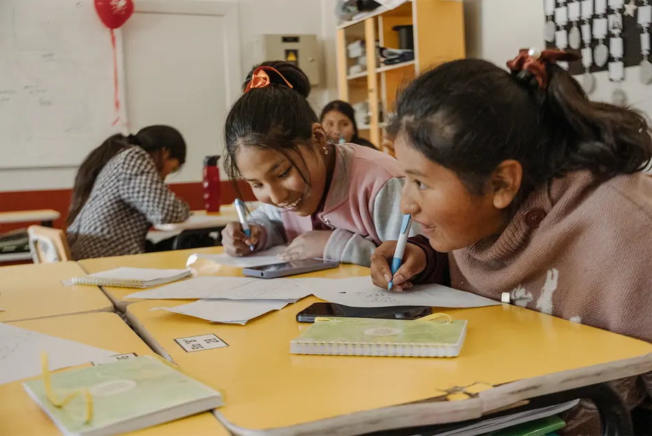 Dos participantes del taller Saphi dibujando sobre una mesa amarilla
