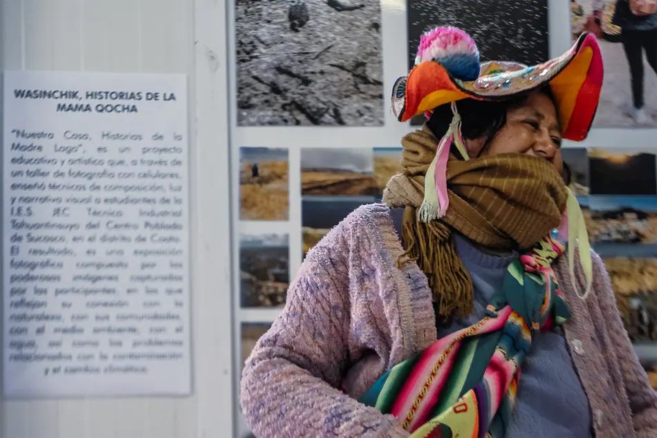 Mujer aymara con sombrero tradicional observando las fotografías de la muestra